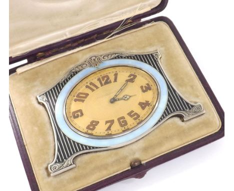 Art Deco silver and enamel strut clock in the original fitted leather case, the oval gilt engine turned dial with luminous Ar