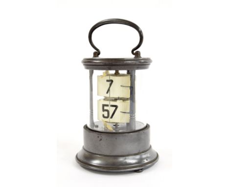 Antique ticket clock, within a cylindrical glazed stepped metal case surmounted by a loop handle, 7" high