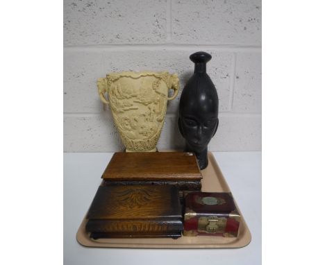 A tray containing a carved tribal bust, three wooden trinket boxes together with an Eastern resin elephants head vase