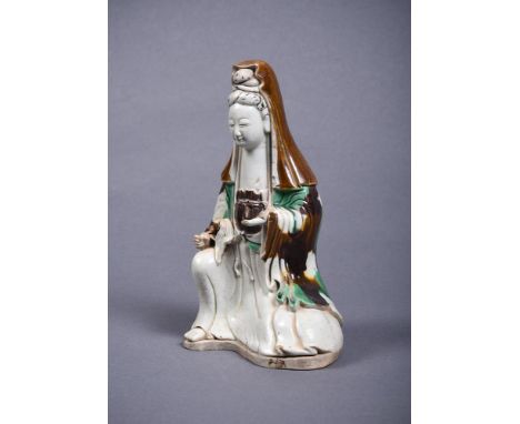 A Chinese Sancai glazed Figure of Guanyin, Kangxi, wearing a high bun covered with a shawl falling over her shoulders, the ro