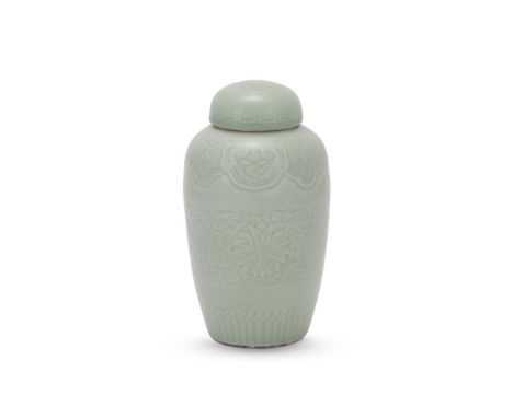 A Chinese celadon jar and cover, late Qianlong, carved with scrolling lotus sprays and foliage, the neck with alternating ruy