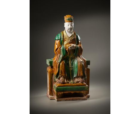 A large Sancai-glazed seated figure of a Daoist deity, Ming dynasty, heavily potted seated on a rectangular throne, wearing a