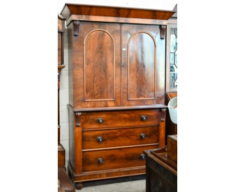 A 19th century mahogany linen press (slides removed and replaced with two brass rails), with arch panelled doors over three d