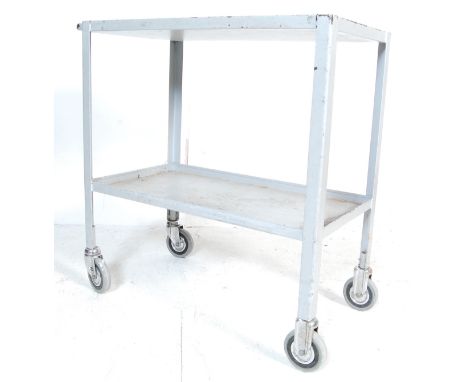 A retro vintage industrial factory two tier trolley having a lipped edge with curved supports raised on rubber wheels. Trolle
