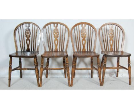 A set of four vintage 20th century oak and elm wheelback windsor chairs having hoopback spindle backrests with saddle seats r