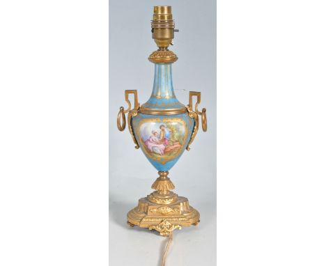 A vintage 20th century porcelain Sevres style lamp base having brass handles and base. The lamp base has a blue background de