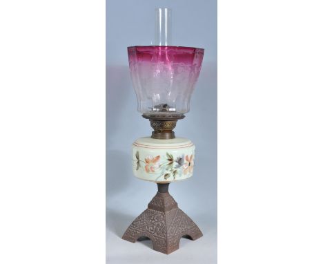 A late 19th century Victorian oil lamp having a cast metal base with a hand painted reservoir decorated with flowers and cran