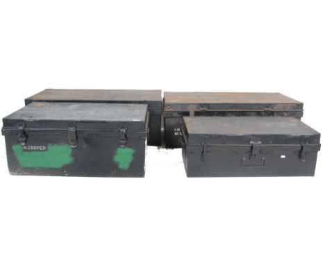 A group of four vintage industrial military metal trunks being black painted with hinged tops and fastenings, some having pai