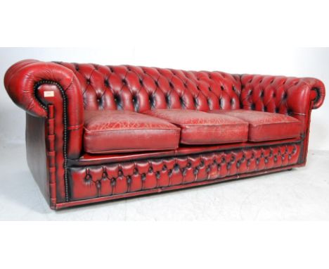 A vintage 20th Century antique style Chesterfield three seater sofa settee in a deep oxblood scarlet red leather having butto