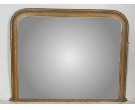 An antique Victorian 19th Century archtop over mantel mirror having a large central glass plate set within a foliate gilt fra