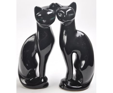 A pair of vintage retro mid 20th Century ceramic black cats each of elongated stylised form having green painted luminous eye