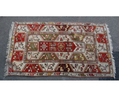 A 20th century Oriental rug having bright and vibrant colours of beige and red being decorated with geometric patterns with c