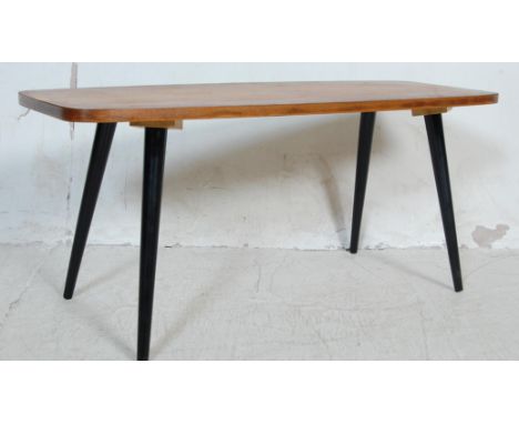 A retro vintage 1970s teak wood surfboard coffee table having curved corners raised on ebonised angular tapering legs.&nbsp;M