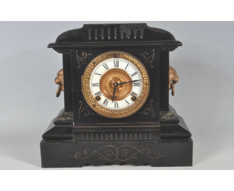 An early 20th century 8 day mantel clock of architectural form having an ebonised metal body with a brass and enamel, roman n