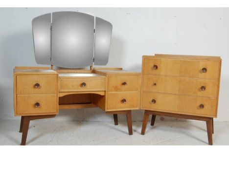 A vintage retro 20th century light oak bedroom suite. The suite comprising of a kneehole dressing table with three adjustable