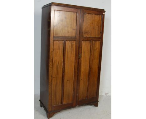 A mid 20th century antique style walnut compact wardrobe. The twin door wardrobe having panel doors with brass lock, fitted i