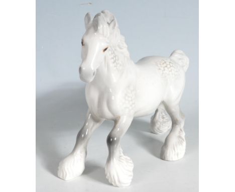 A Beswick ceramic horse figurine in the form of a dappled grey cantering shire horse, marked Beswick to the belly. Measures a