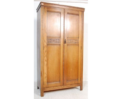 A mid century carved oak Jacobean revival bachelors wardrobe. Raised on style legs with fielded panel doors having embellishe