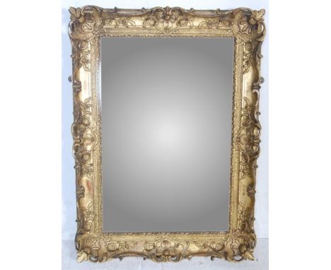 A large decorative antique gilt revival baroque wall - over mantel mirror. The mirror of cushion form with stunning embellish