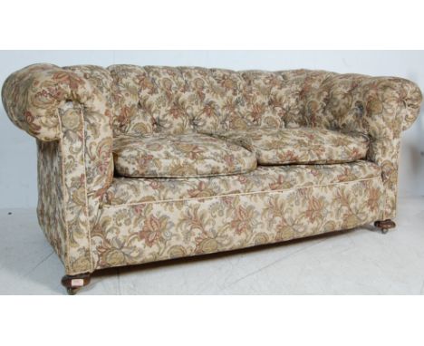 A late Victorian 19th century chesterfield sofa settee having barrel arms with a button backrest raised on bun feet. Upholste