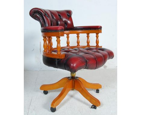 A 20th century antique style ox blood leather Chesterfield Captains deep button back yew wood framed swivel office / desk cha