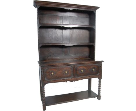 A 1920's oak dresser having a frieze top with a two shelved open front display cabinet below the base having two twin handled