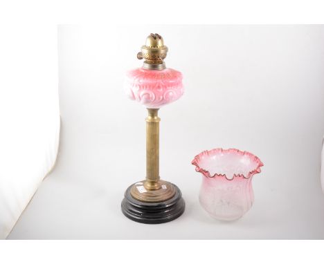 Victorian oil lamp, pink tinted opaque glass shade, fluted brass column with shade and chimney, 77cm overall.