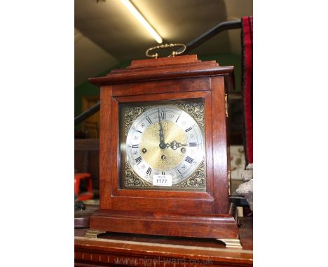 A wooden cased German chiming Mantle Clock with brass bracket feet and carrying handle, complete with pendulum and key.