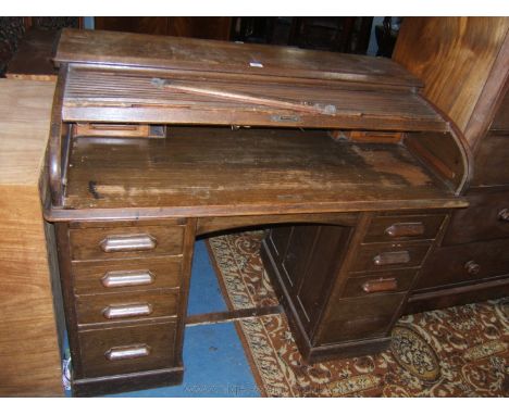 A 1930's ministry Oak Lebus Desk, having moulded edge top over the tambour roll-top opening to reveal six pigeon holes, four 