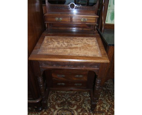 A late Victorian Mahogany Davenport style desk, having carved gallery upstand and carved detail in finial decorated supports,