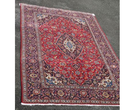 A fine Kashan Carpet with classic central medallion on red field and flower heads on purple border. 9ft 7in x 6ft 7in (300cm 