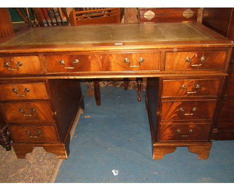 A reproduction Mahogany finished Kneehole Desk, having moulded edge top with tooled green leather insert central wide frieze 