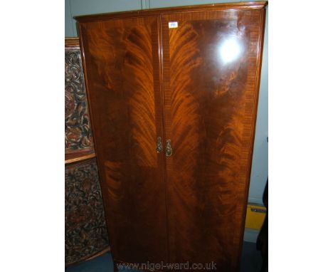 A reproduction Mahogany finished Georgian style two door narrow Wardrobe, having moulded top over the pair of opposing cross 