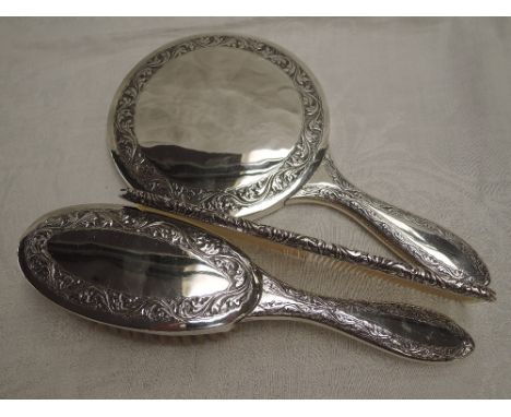 A Pakistani silver three piece dressing table set having an engraved border, and presentation inscription to mirror handle by