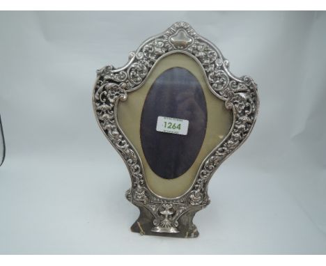 A Victorian silver photograph frame of cartouche form having a silver border with scroll, cherubic mask and floral decoration