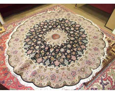 A modern Tabriz circular wool rug with scalloped edge, salmon pink border and foliate design on a black ground, 200cm diamete