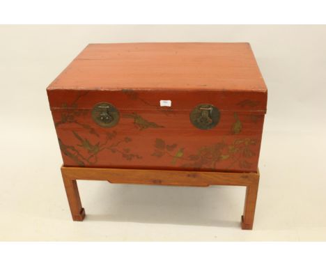 Chinese red lacquer trunk decorated with birds and foliage mounted on a later hardwood stand, 33ins wide overall27ins high x 