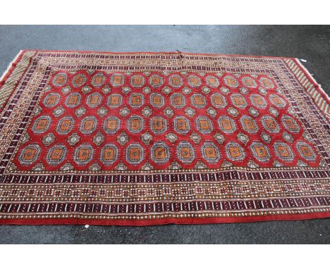 Pakistan Bokhara design carpet having four rows of twelve gols with multiple borders on a wine ground, approximately 112ins x