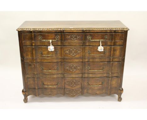 19th Century French oak serpentine fronted commode, the carved moulded top above four drawers with brass handles, raised on l