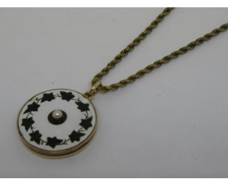 15ct Gold and enamel locket, enamel decorated with ivy leaves and a cultured pearl on a white ground suspended from a rope li
