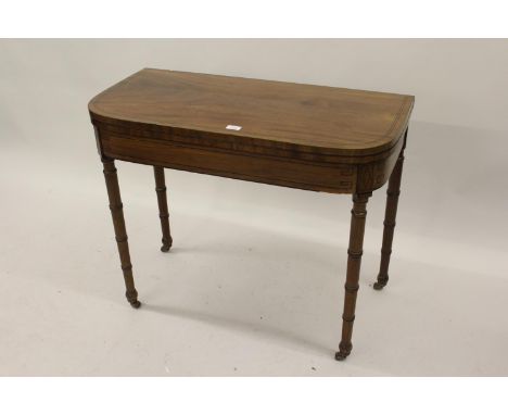 George III mahogany and line inlaid D-shaped fold-over card table raised on turned tapering supports with brass casters 