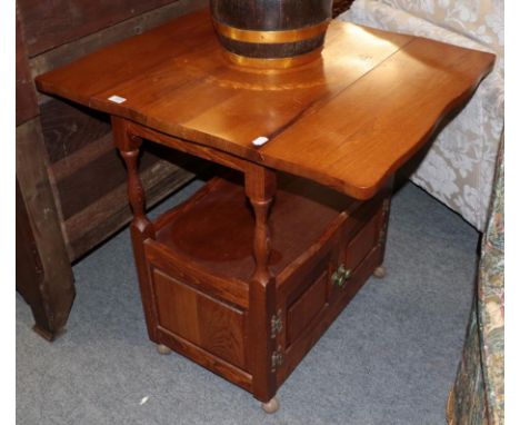 A modern oak occasional table, the rectangular top with drop leaves above a shelf section over a pair of cupboard doors, movi