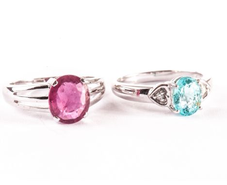 Two modern 18ct gold and gem set dress rings, one with red stone in tri-split shoulder, the other with light blue stone havin