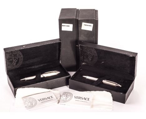 A pair of Versace white metal cased pens, one a cartridge pen, the other a roller ball, each presented in black leather velve