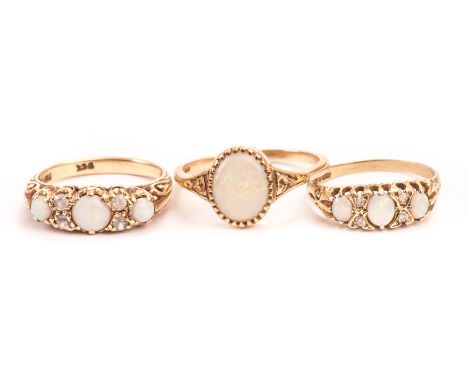 Three 9ct gold and opal set dress rings, one with a single oval opal, the other two with three opals and clear stones (3) 