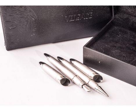 A pair of Versace white metal cased pens, one a cartridge pen, the other a roller ball, each presented in black leather velve
