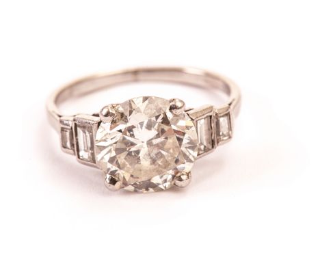 An impressive Art Deco diamond engagement ring, having a brilliant cut of approx 2.7ct set in four claws with two baguette cu
