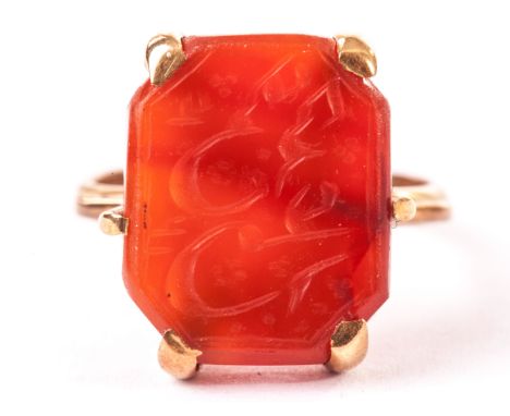 A middle eastern signet ring, the yellow metal ring and mount supporting a carved carnelian panel with intaglio script 
