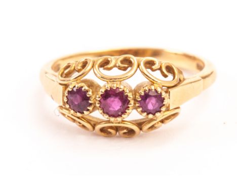 An 18ct gold and ruby dress ring, having three round cut stones in pierced mount, hallmarked 