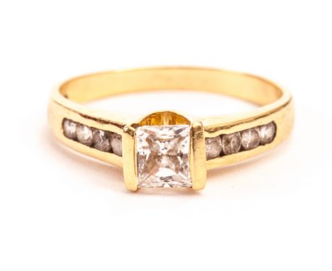 An 18ct gold and white sapphire ring, having a square cut central stone and round cuts in channel set shoulders, hallmarked 